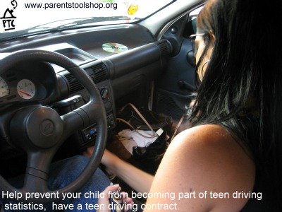 Young girl behind steering wheel with cell phone in hand